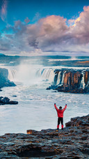 Man Standing on The Edge of The Cliff Facing The Waterfall
