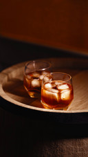 A glass of whiskey with ice on a wooden background
