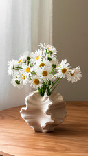 A bouquet of daisies in a ceramic vase on a wooden table