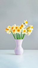 Pink vase on the white table with buquet of narcissus