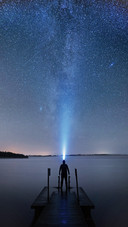 A Man with Flashlight Standing on A Pier by A Lake