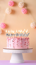 Birthday cake with burning candles on violet table