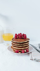 A stack of pancakes decorated with raspberries