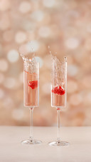 Two Champagne Glasses Splashing with Fruit in It