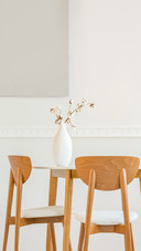 Closeup of flowers in white vase on wooden dining table