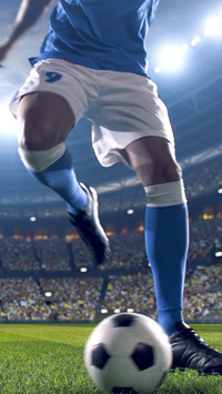 Soccer player kicks the ball on the soccer stadium