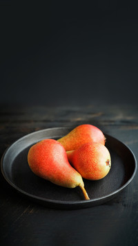 Healthy organic pears in black metal bowl on dark background