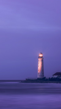 A lighthouse on the coast of the sea at dusk