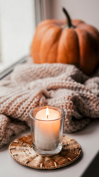 Cup of coffee, pumpkin, dried autumn leaves on window
