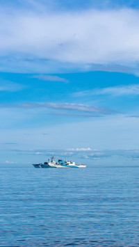 Distant Navy ship on vast blue Pacific Ocean