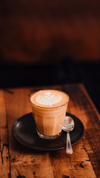 Mug of flat white coffee with latte art on wooden table