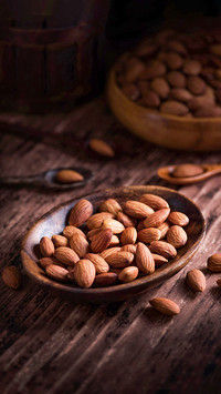 Almonds on a wooden cup and spoon with copy space