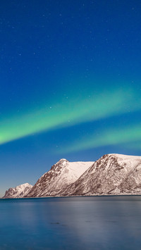 Polar lights over fjord mountains with many stars