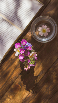 Open book and vase on wooden table