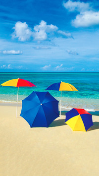 Four umbrellas on the smooth sands of an empty beach in