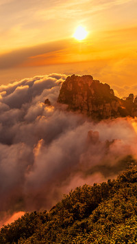 The sea of clouds and the glow of the sunset tint the