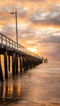 A vertical shot of a pier with the beautiful view of sunset