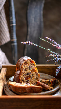 A piece of a sponge cake with dried fruits on a wooden tray