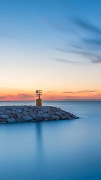 Seascape sunset with rocks and little lighthouse