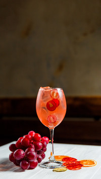 An orange cold summer alcoholic cocktail in a wine glass