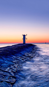 A windmill as lighthouse at the end of a long pier