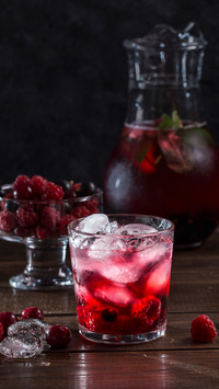 Berry lemonade in a transparent glass on a dark background