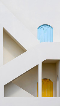 Two colorful doors on the side of a white building
