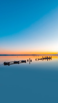 A broken wooden pier on the lake at sunrise time