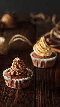 Two brown chocolate cupcakes on wood background