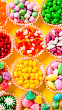 Multicoloured candy and jellybeans in paper cups overhead