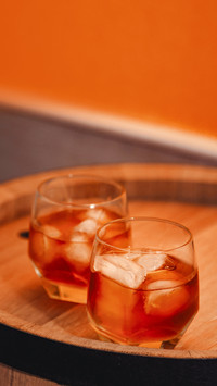 A glass of whiskey with ice on a wooden background