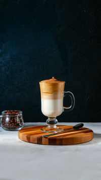 Iced Dalgona Coffee with Sifting Cocoa on Light Grey