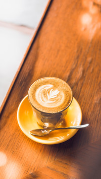 The coffee on yellow plate placed on the wooden table