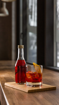 Glass and bottle of red fresh alcoholic cocktail with ice