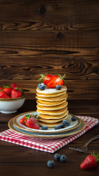 Blueberries and jars of berries on wooden background