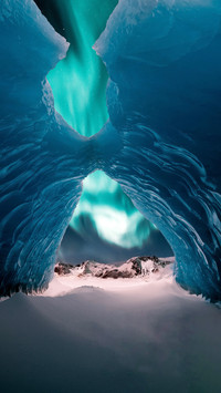 Person in the Middle of Ice Cave with Aurora