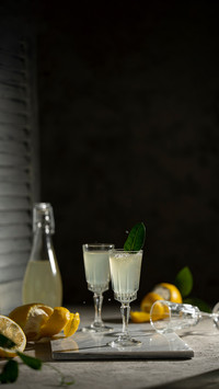 Limoncello in a little glasses and bottle on a black backgro