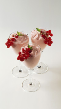 Three redcurrant cream desserts served in stemmed glasses