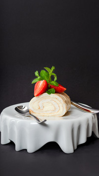 Pavlova roll dessert with strawberry on white unusual plate