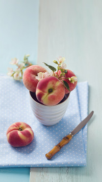 Peaches in bowl with knife on tablecloth