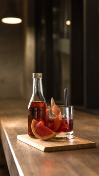 Bottle and glass of red fresh alcoholic cocktail with ice