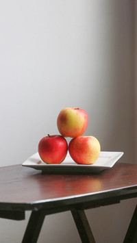 Apples on white plate by the window