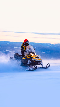 A man is riding snowmobile in mountains