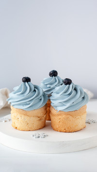 Three cupcakes with light blue cream on a white plate