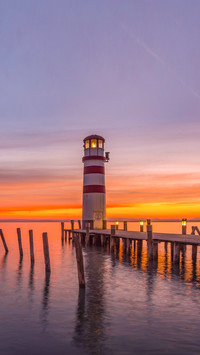 Wooden jetties and lighthouse at sunset by the spring lake