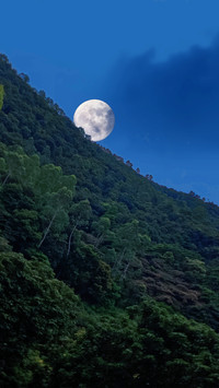 The moon rose slowly beside the mountain