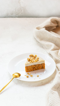 A slice of carrot cake with walnuts on a white plate