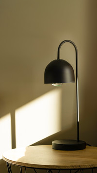 Black lamp on the table with sun light near bed