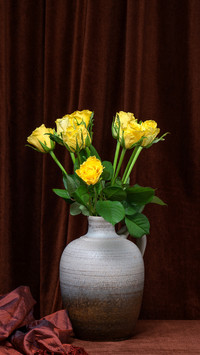 A beautiful bouquet of yellow roses in a gray vase