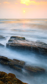 Waves and rocks in sunset in long exposure